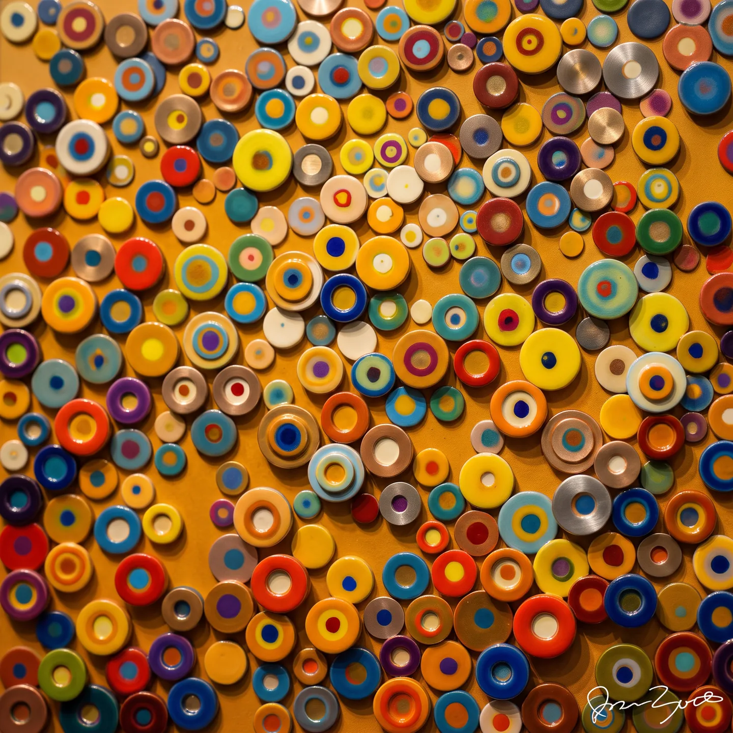 Dimensional interpretation of Stroker Circo CDXIV: concentric glazed ceramic discs in yellow, orange and blue mounted at varying depths as a wall relief.